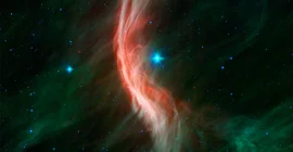 Der „Runaway Star“ Zeta Ophiuchi – in der Nähe der Bildmitte und etwa 20-mal so massereich wie die Sonne – bewegt sich mit 24 Kilometern pro Sekunde nach links. Aufgrund seiner Geschwindigkeit erzeugt er wie ein Schiff, das durch die kosmische See pflügt, die bogenförmige interstellare Bogenwelle oder den Bogenschock, der in diesem Infrarotporträt zu sehen ist. Foto: NASA, JPL-Caltech, Spitzer Space Telescope.