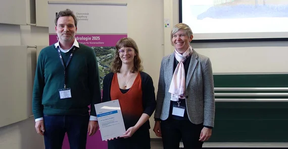 Foto von drei Personen, die bei einer Preisverleihung zusammenstehen