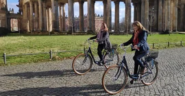 Das Bild zeigt zwei Frauen auf Fahrrädern auf dem Campus Am Neuen Palais
