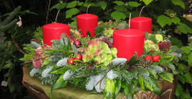 Adventsgesteck mit vier roten Kerzen.