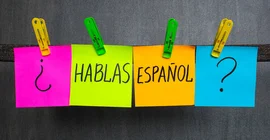 vier Post-its, die mit Wäscheklammern an einer Leine befestigt sind, auf denen steht: "hablas espanol?"