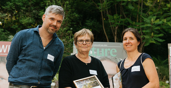 Preisträgerin posiert mit zwei Personen für ein Foto