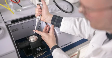 Mann bringt Flüssigkeit mit Pipette auf ein elektronisches Messgerät auf