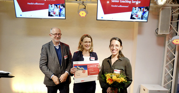 Das zweitplatzierte Team „Funster“ beim diesjährigen Senior Coaching Service Wettbewerb erhält das Preisgeld in Form eines symbolischen Schecks von Prof. Dr. Dieter Wagner. Foto: Tilo Bergemann.