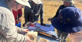 Forschende beugen sich über Geräte bei einer Übung im Gelände