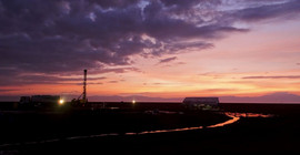 Bild mit Sonnenuntergang und Bohrturm im Hintergrund