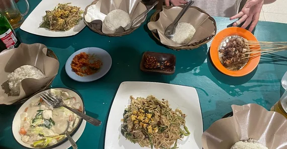 Blick auf eine Tischoberfläche auf der viele verscheidene Speisen in verschiedenen Schalen zu sehen sind. Beilage ist jeweils Reis.