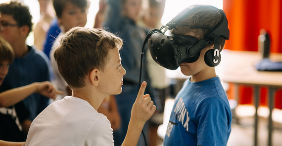 Zwei Kinder im Fokus. Eins trägt eine VR-Brille.