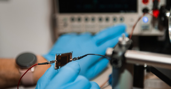 Zwei Hände, die ein Bauteil für eine Solarzelle halten.