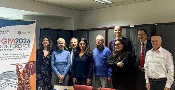 Gruppe von Menschen posiert neben einem Tagungsposter für ein Foto