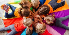 Kitakinder liegen zusammen in einem Kreis auf dem Boden.