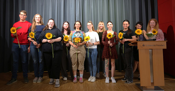 Gruppenfoto der ausgelernten Auszubildenden. Alle halten je eine Sonnenblume in den Händen.