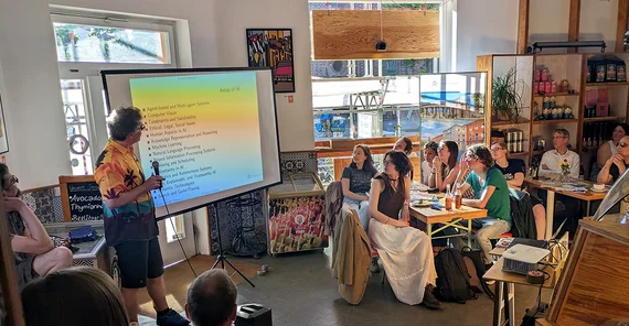 Blick in den Gastraum eines Cafés, wo ein Forscher einen Vortrag hält
