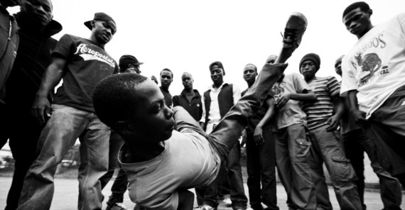 Gruppe von jungen Menschen im Kreis, in der einer in der Mitte tanzt.