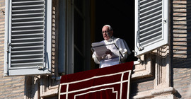 Papst Franziskus steht am Fenster und liest von einem Blatt ab