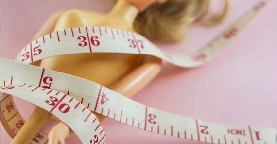 Symbolbild: Barbie-Puppe mit Maßband umwickelt.