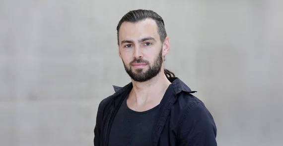 Steffen Hagemann im Porträt vor einer grauen Betonwand am Campus Griebnitzsee.