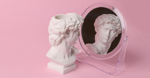 Bust of David admiring himself in a mirror on a pink background. Symbolic representation of narcissism.
