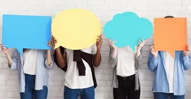 Eine Reihe von Menschen vor einer Wand. Ihre Gesichter verdecken sie mit großen bunten Sprech- oder Denkblasen.