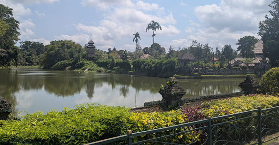 Taman-Ayun-Tempel, malerische Szenerie am Wasser, Palmen und blauer Himmel