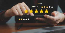 Hände eines Menschen, der ein Tablet hält, drumherum sind Sterne von Bewertungen eingeblendet