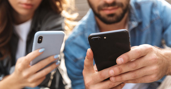 Eine Frau und ein Mann halten ein Smartphone in den Händen.