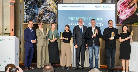 Gruppenfoto von sieben Menschen auf einer Bühne
