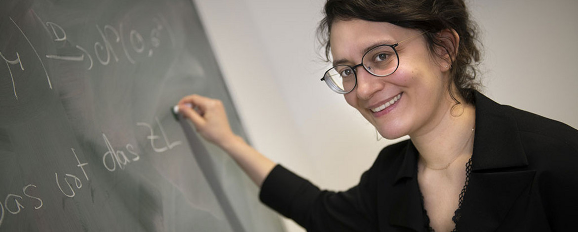 Frau steht an der Tafel und schreibt etwas - 