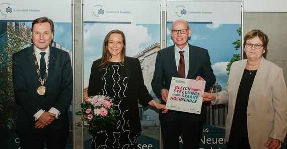 Vier Personen posieren für ein Foto.