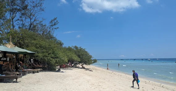 Menschen an einem tropischen Strand mit Meer und Palmen