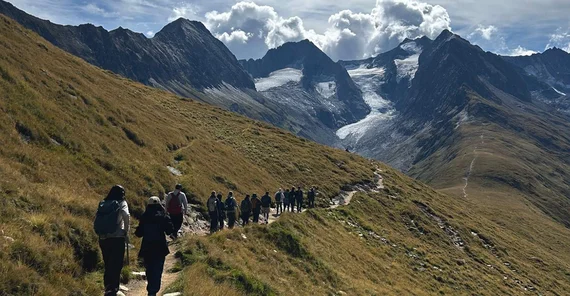 People hiking along a small pathway towards to glacier in the the background