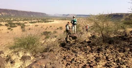 Drei Menschen vor einer Savannenlandschaft