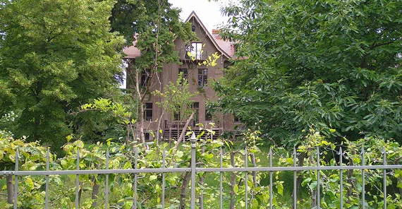 Villa in der Karl-Marx-Straße in Potsdam über einen Zaun hinweg fotografiert.