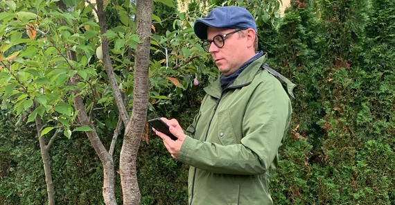 Mann mit einem Smartphone im Grünen.