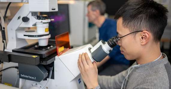 Van-Cuong Pham sitzt an einem Mikroskop.