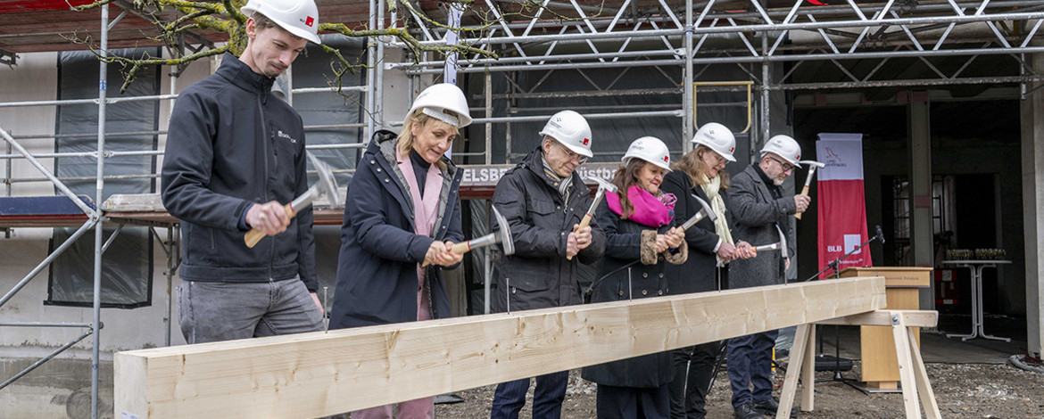 6 Menschen hämmern Nägel in einen großen Balken - 