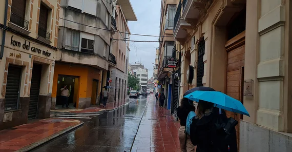 Verregnete Gasse in Spanien, die Studierenden haben Regenschirme aufgespannt