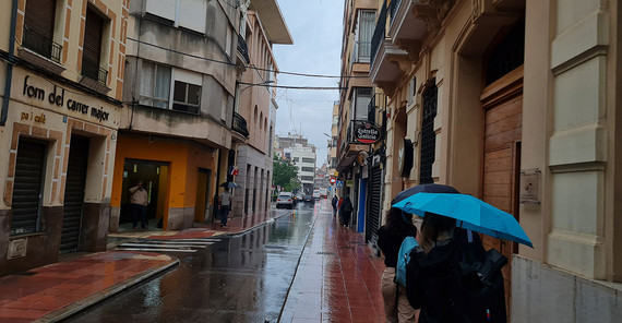 Verregnete Gasse in Spanien, die Studierenden haben Regenschirme aufgespannt
